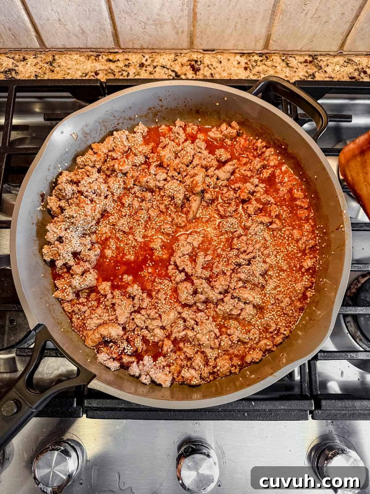 ground turkey, uncooked qunioa, broth, and enchilada sauce in a skillet.