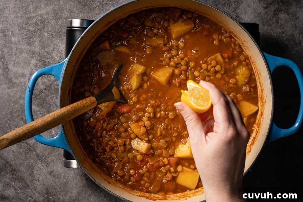 Hearty Lentil and Potato Soup Recipe for Comforting Weeknight Meals 15 lemon wedge being squeezed over soup in pot