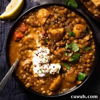 lentil potato soup in bowl with spoon in bowl and lemon wedge on the side