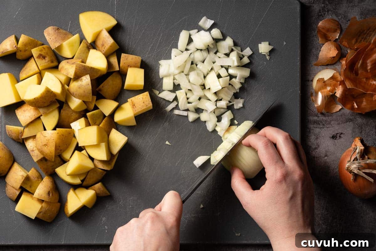 Hearty Lentil and Potato Soup Recipe for Comforting Weeknight Meals 6 onion being chopped on cutting board with chunks of potatoes on the side