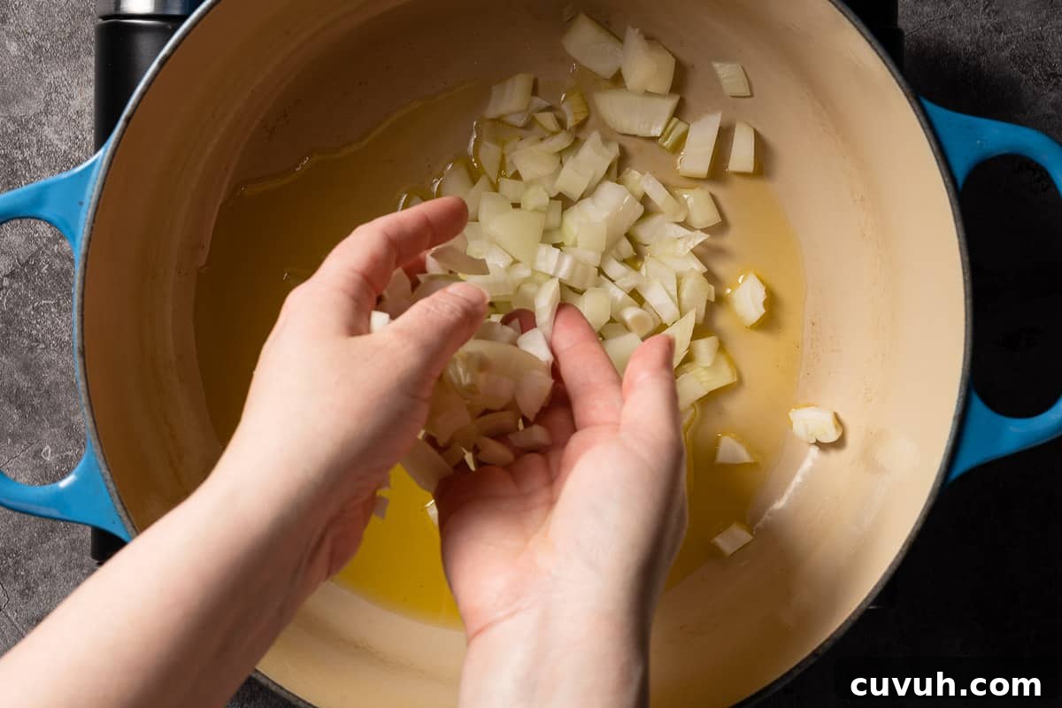 Hearty Lentil and Potato Soup Recipe for Comforting Weeknight Meals 7 hands adding chopped onion into pot with oil