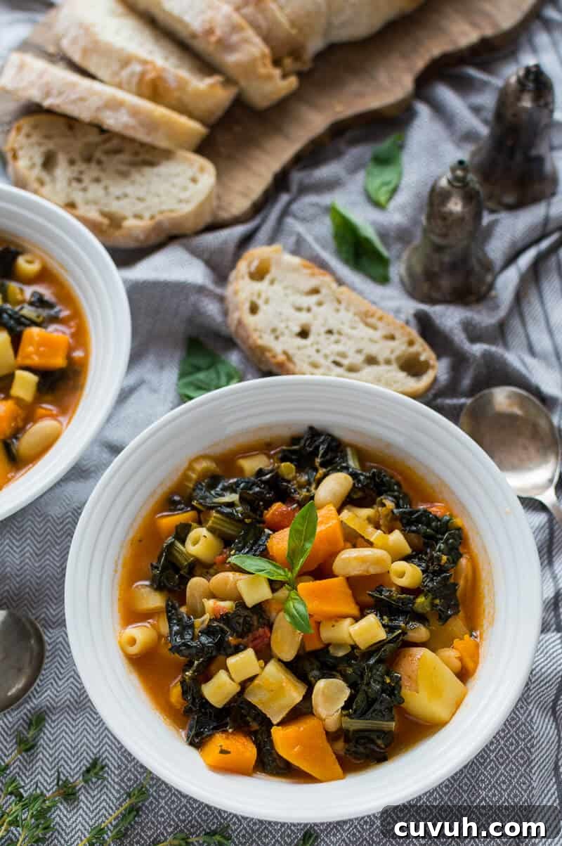 Autumn Vegan Minestrone Soup with Seasonal Vegetables 3 A white bowlful ofvegan Autumn minestrone soup on a grey tablecloth with sliced ciabatta.
