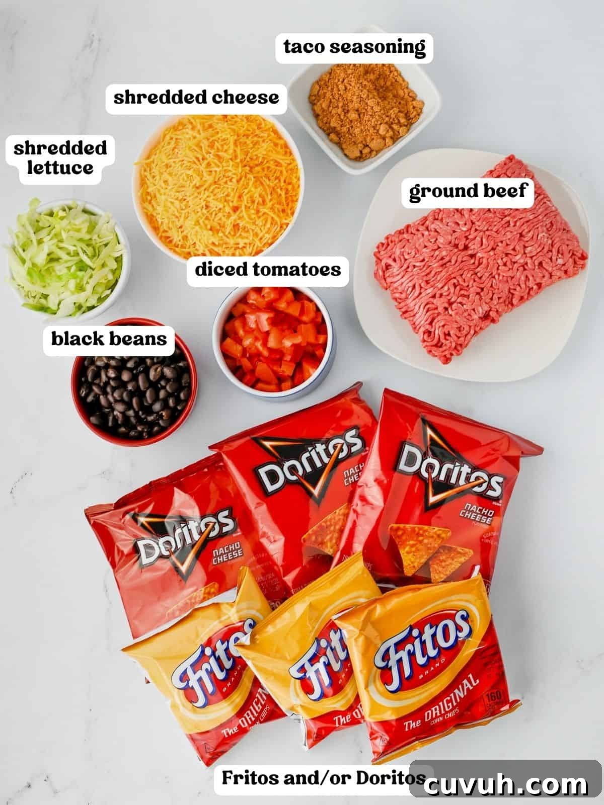 How to Make Walking Tacos: Quick Party-Friendly Recipe 3 Walking taco ingredients including shredded cheese, taco seasoning, raw ground beef, shredded lettuce, black beans, diced tomatoes, and several unopened bags of Doritos and Fritos.