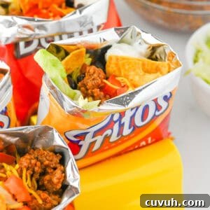 How to Make Walking Tacos: Quick Party-Friendly Recipe 7 Fritos walking tacos with toppings like shredded cheese, beans, sour cream, and lettuce.