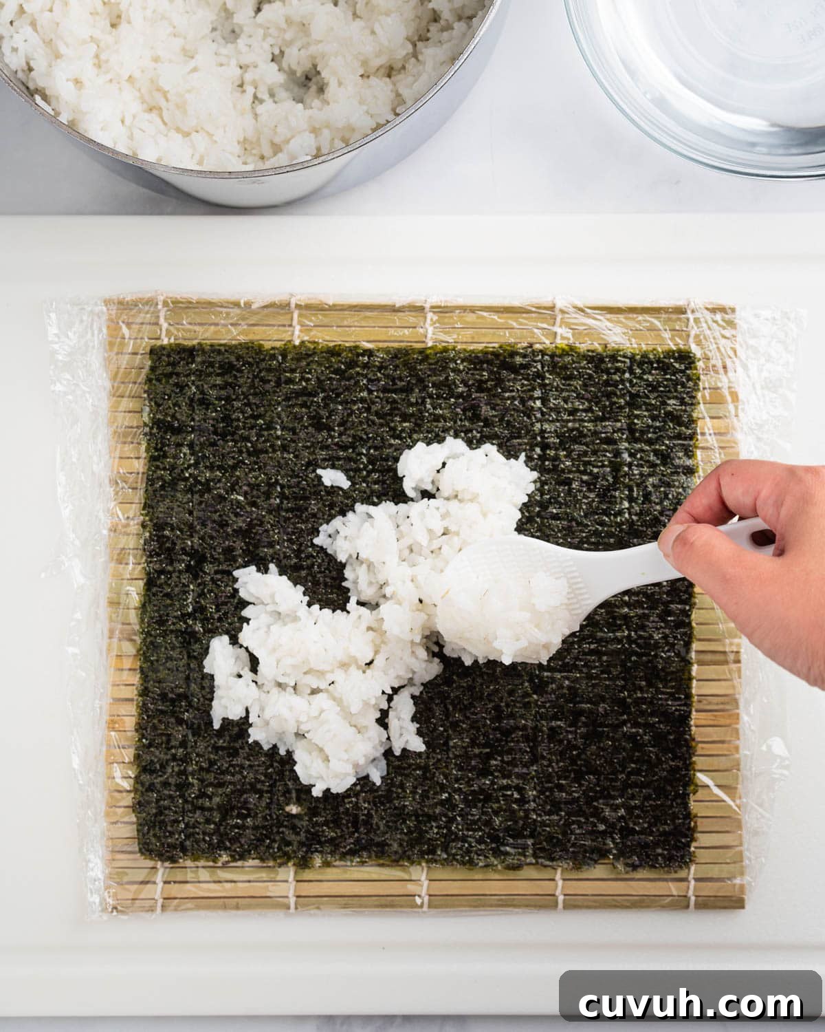 Spreading an even layer of rice on the nori sheet.