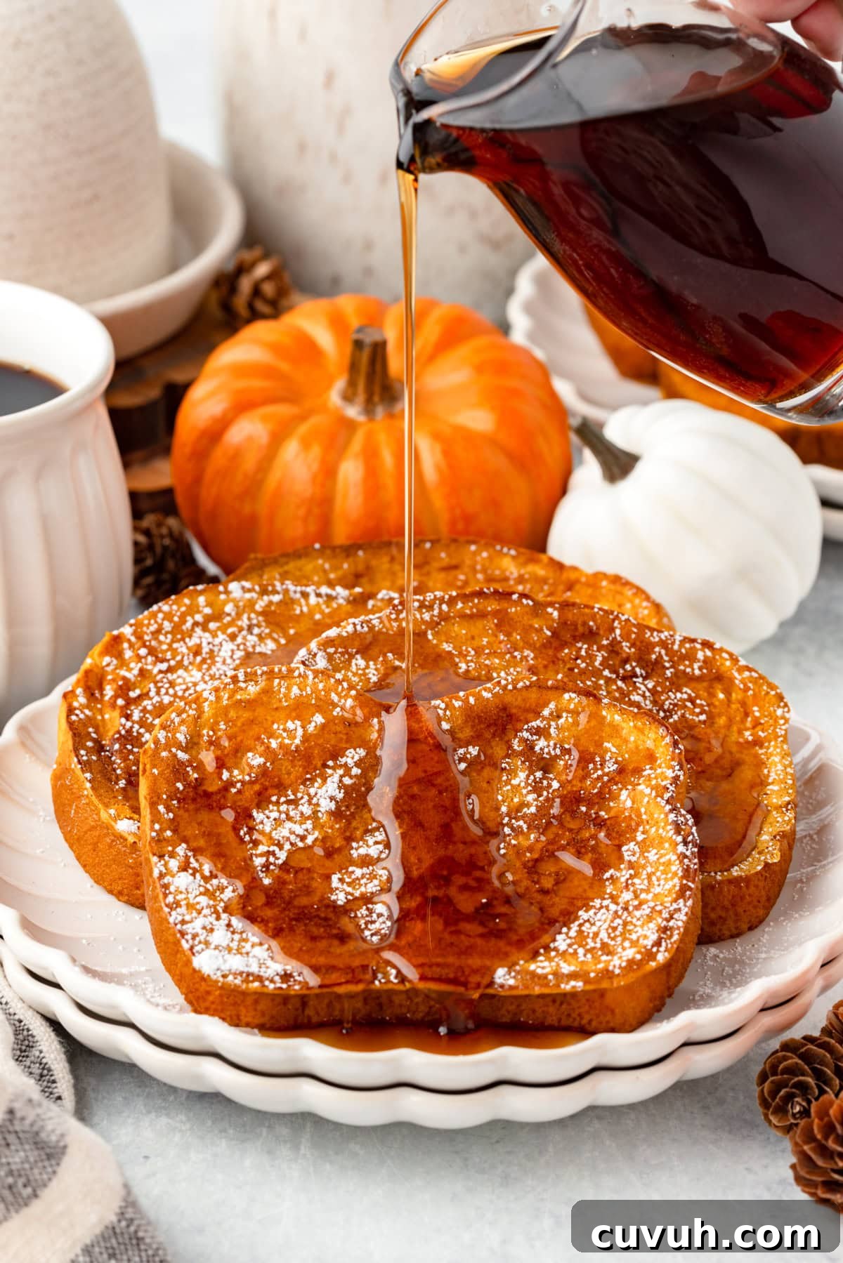 A close-up of syrup being poured over three slices of pumpkin French toast.