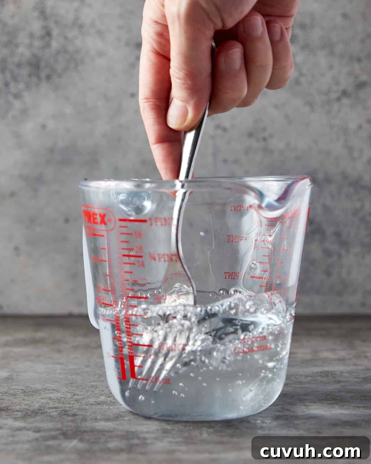 Photo showing someone stirring glycerin and water together with a fork in a jug.