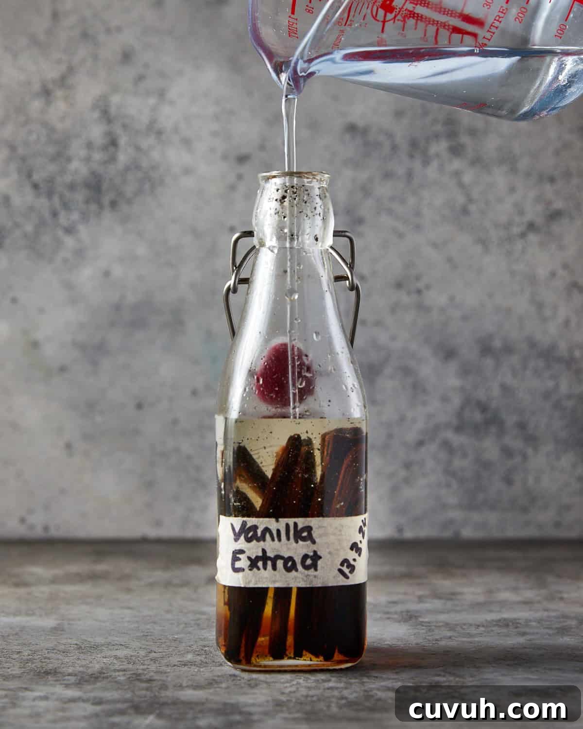 Photo showing vanilla pods in a bottle and the glycerin and water mixture being poured into the bottle with them.