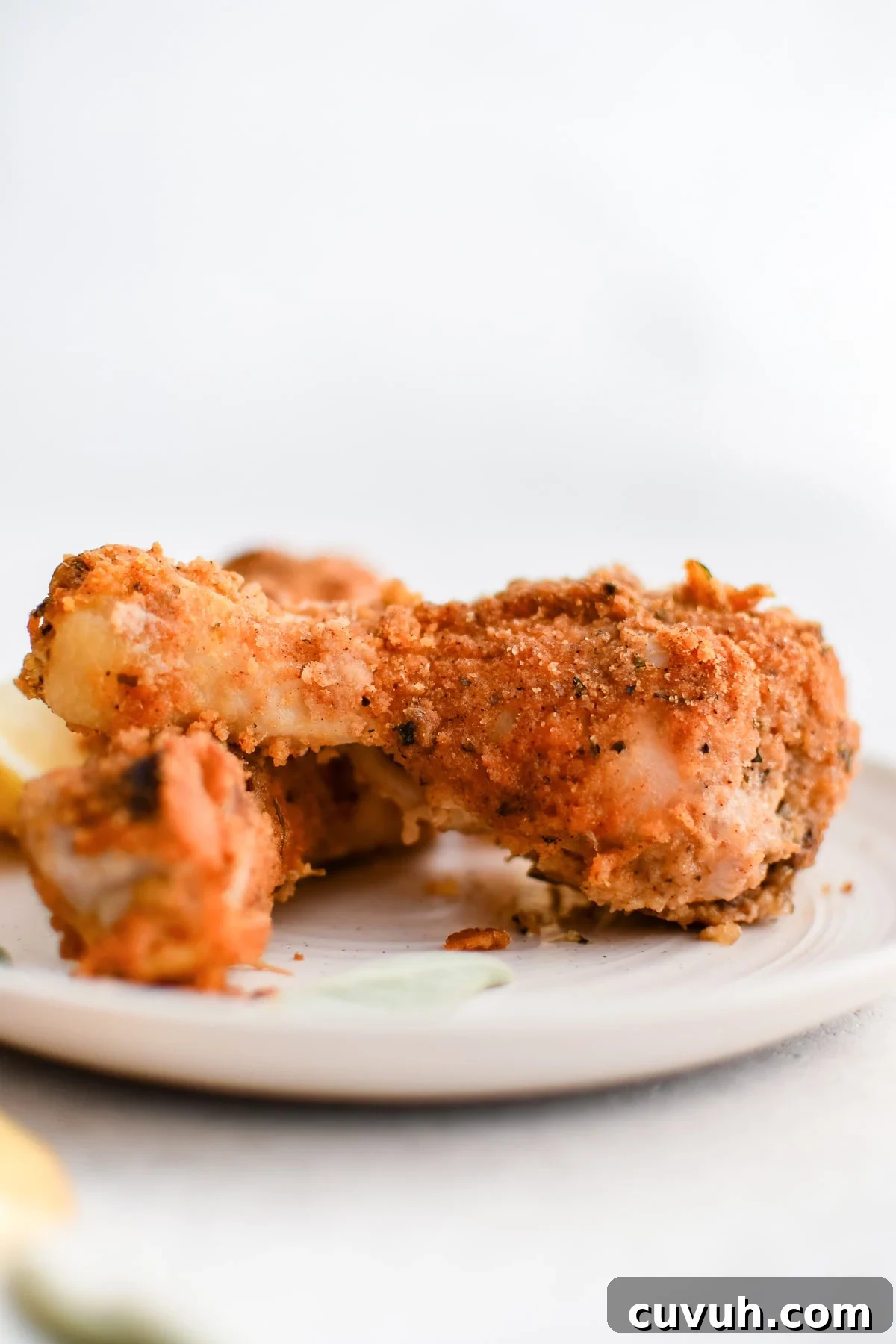 Crispy Shake-and-Bake Chicken Recipe for Perfect Weeknight Meals 12 Two homemade shake and bake chicken drumsticks on a white plate.