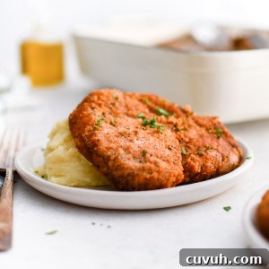 Crispy Shake-and-Bake Chicken Recipe for Perfect Weeknight Meals 13 White plate with mashed potatoes topped with one crispy golden shake and bake pork chop.
