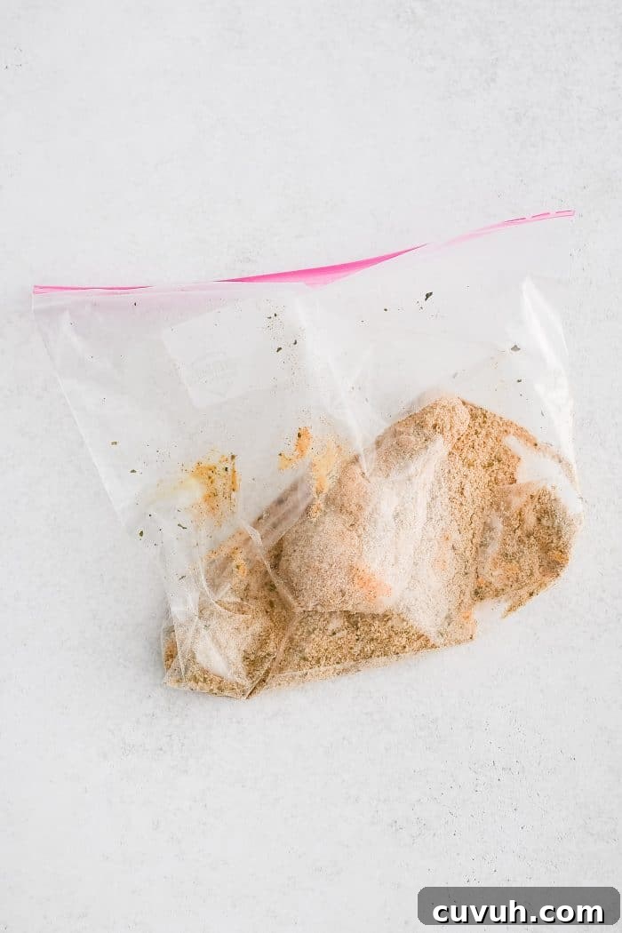 Crispy Shake-and-Bake Chicken Recipe for Perfect Weeknight Meals 9 Ziplock bag filled with raw chicken drumsticks coated in melted butter and Dijon mustard and homemade shake and bake seasoning.