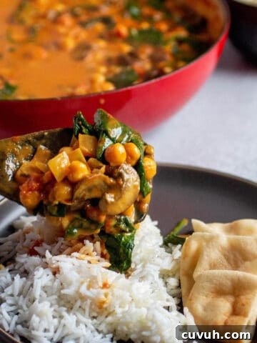 Plate with rice and naan. A wooden spoon pouring on a chickpea, spinach curry mix.