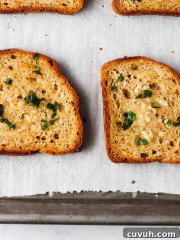 4 slices of gluten free garlic bread with parsley on top on a baking sheet