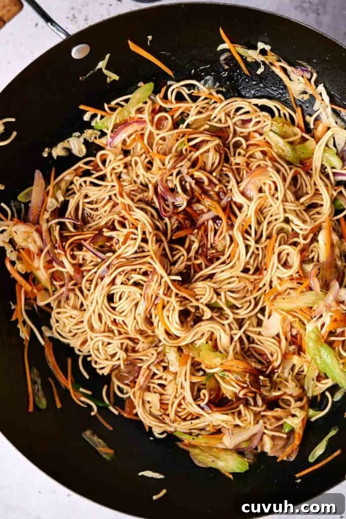 Homemade Chicken Chow Mein Recipe That Beats Takeout 4 A wok containing stir-fried chow mein noodles mixed with vegetables like shredded carrots, cabbage, and onions.