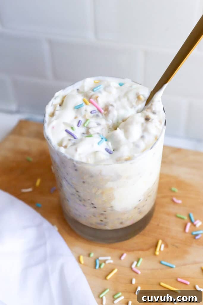 Birthday Cake Overnight Oats — High-Protein Breakfast Recipe 3 high protein birthday cake overnight oats in a mason jar topped with greek yogurt and rainbow sprinkles with gold spoon