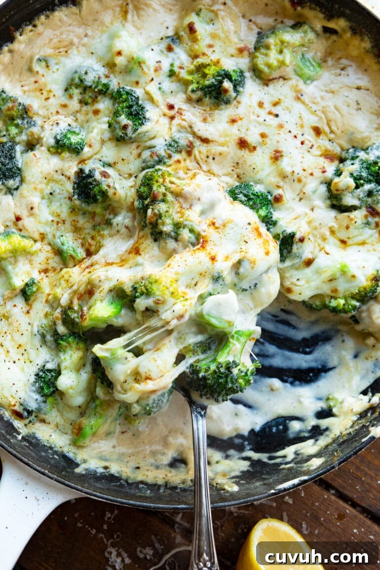 a photo of creamy garlic parmesan broccoli being stirred in a skillet