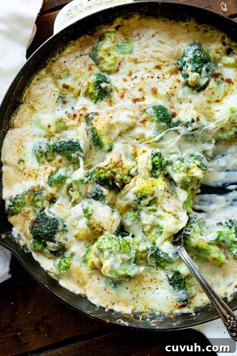 a photo of creamy cheesy broccoli being stirred in a large skillet