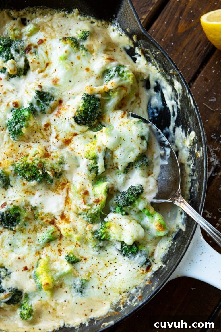 a photo of a skillet full of creamy garlic broccoli being scooped up with a large metal spoon