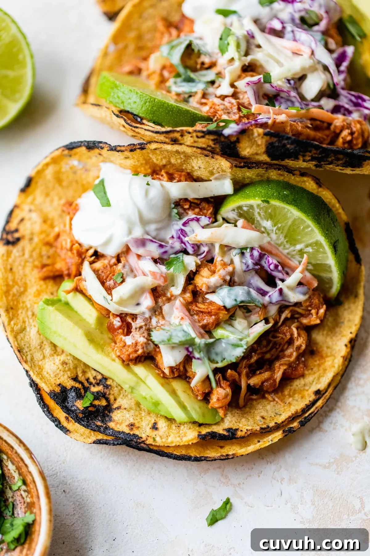 tacos with chicken, slaw, avocado, and a lime wedge