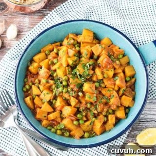 Bombay Potatoes and Peas in a blue skillet. Small dish or rice in the background.