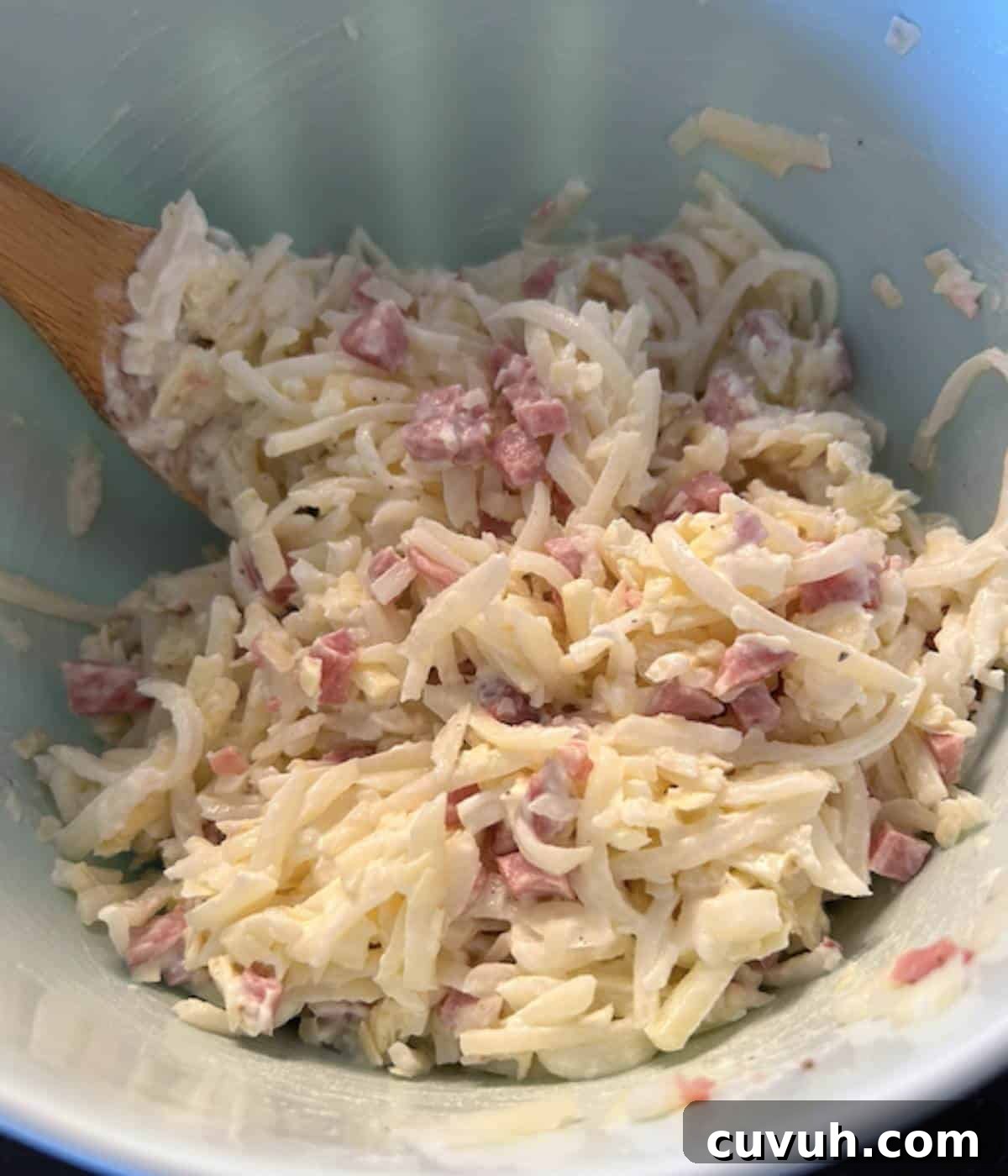 Casserole ingredients in a bowl with wooden spoon.