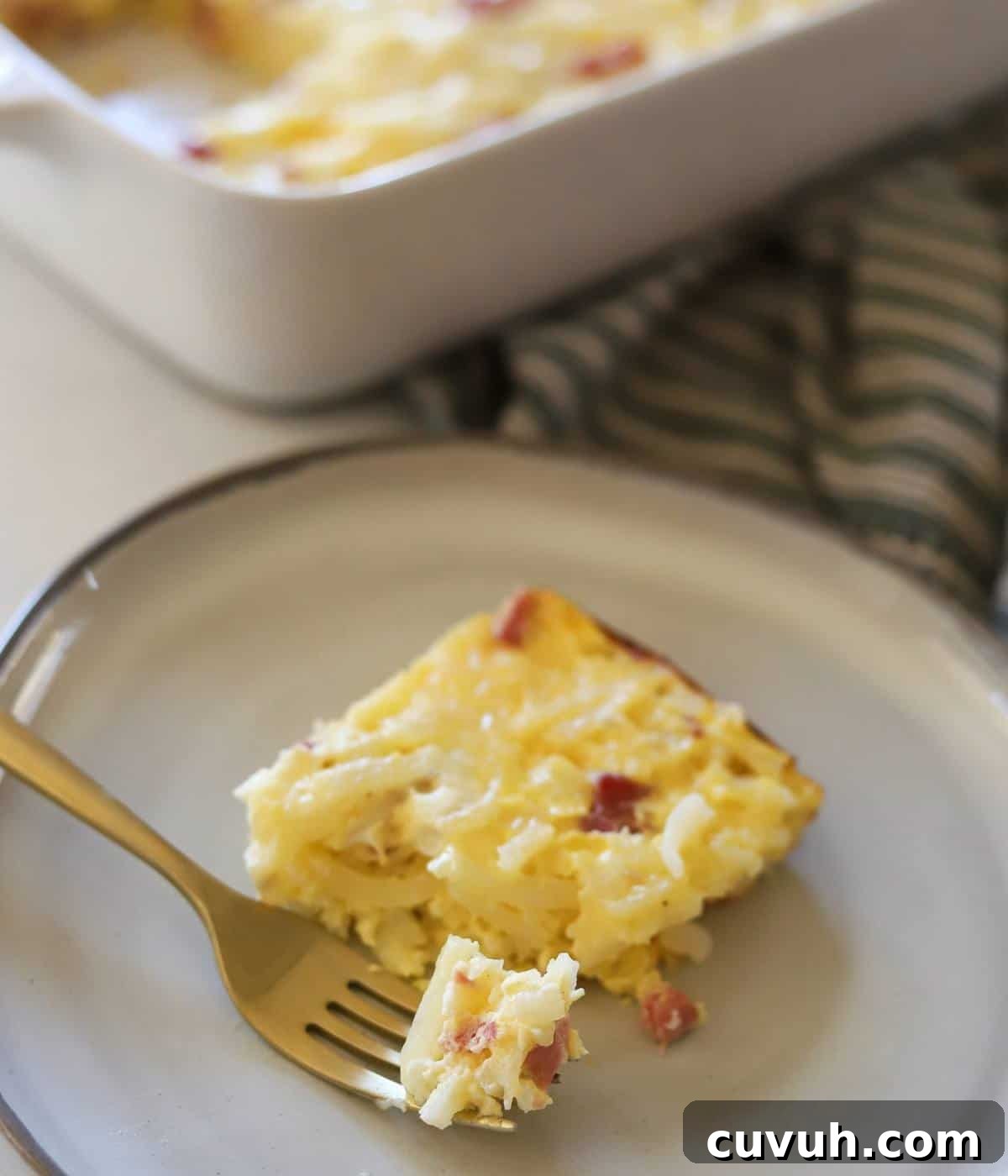 Slice of ham egg hashbrown casserole on plate.