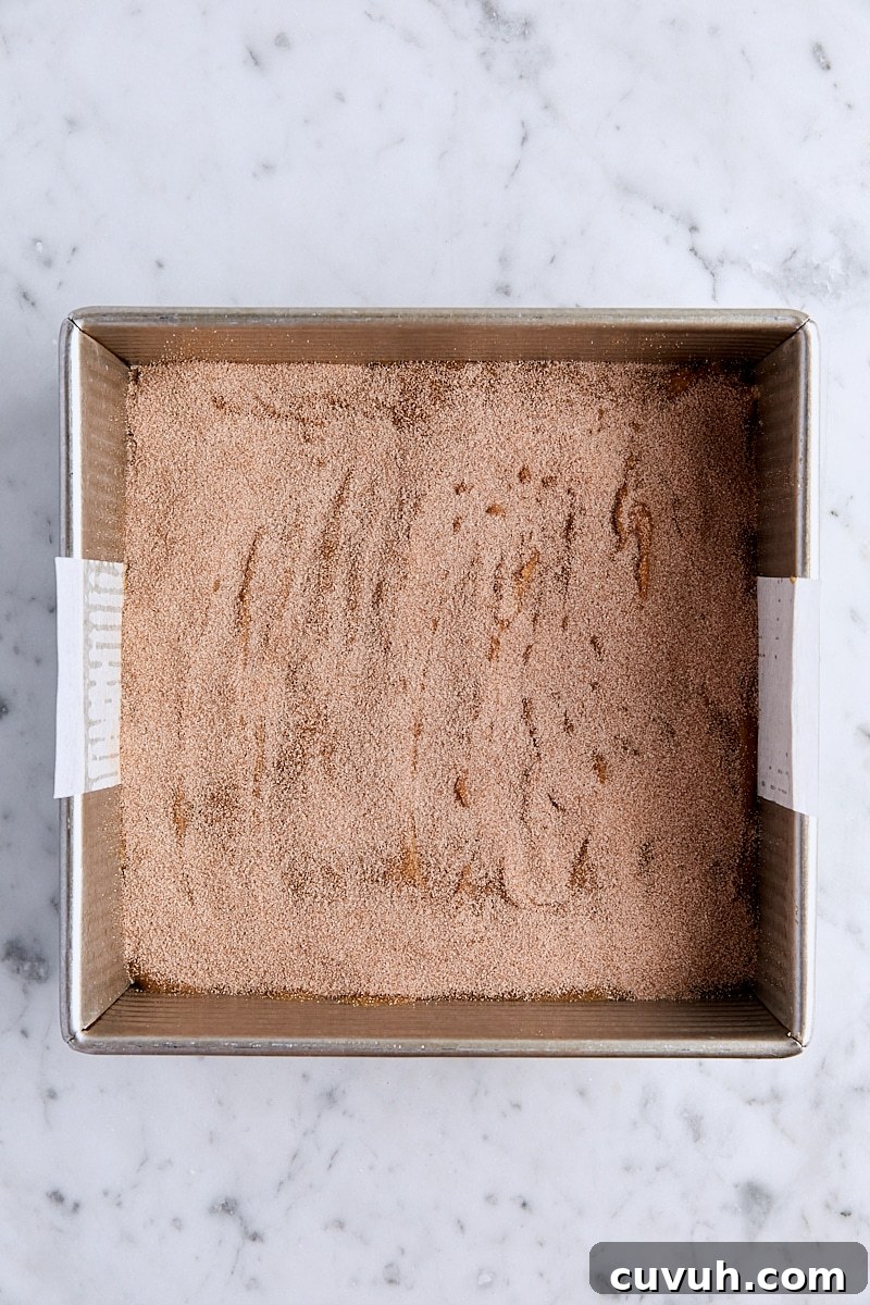Blondie batter topped with cinnamon-sugar in parchment-lined square pan