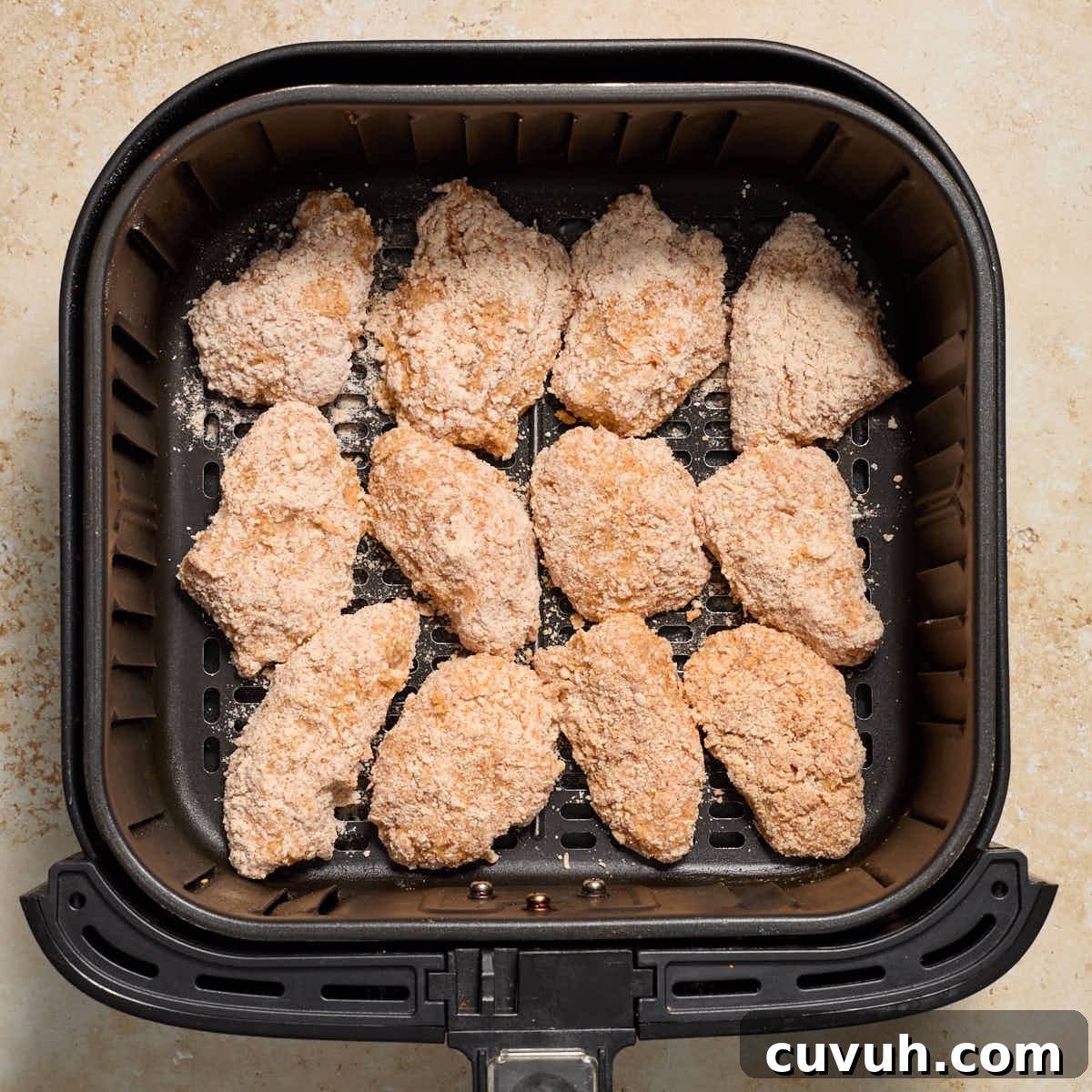 Breaded chicken pieces arranged in a single layer in an air fryer basket.