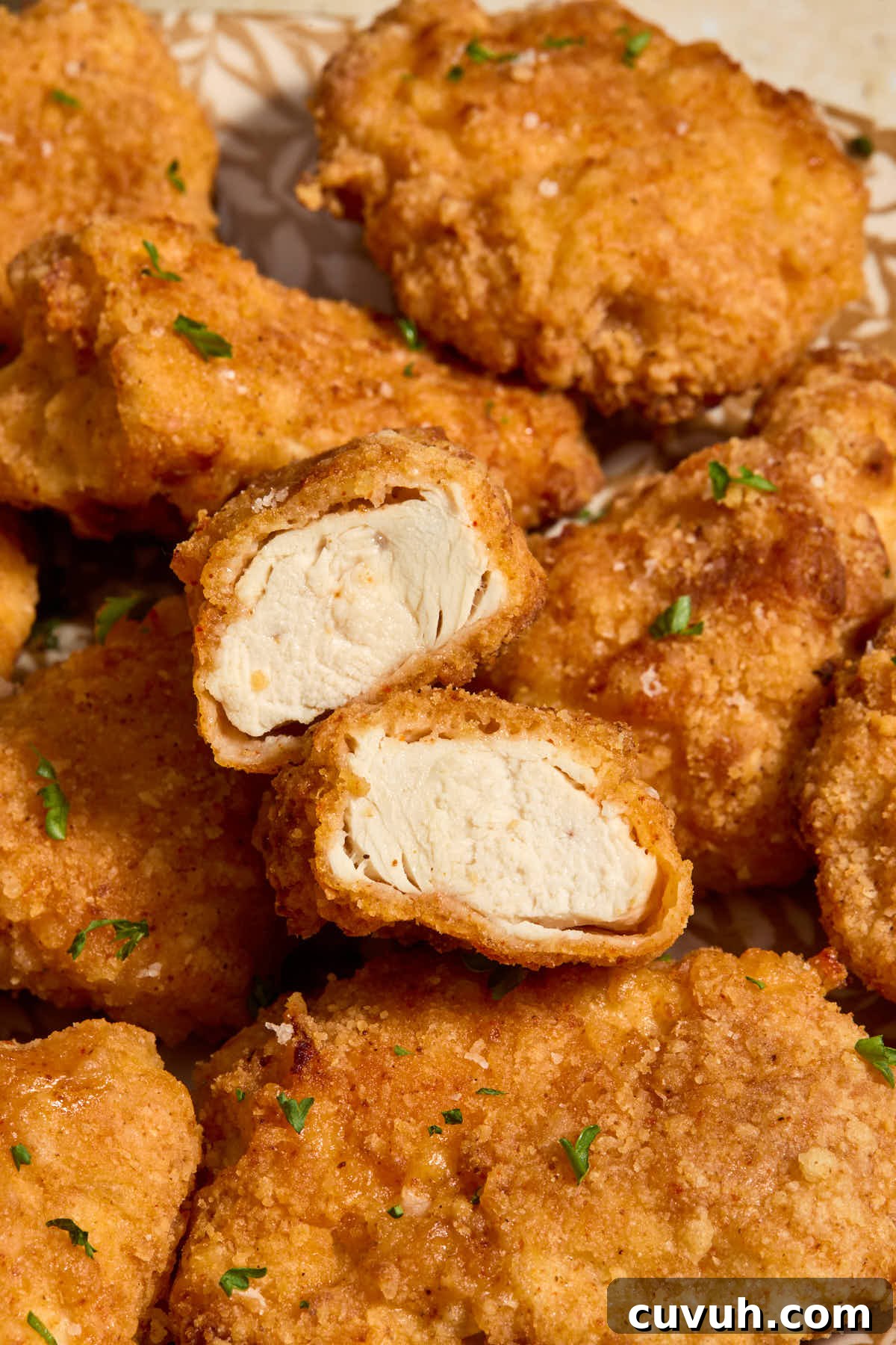 Close up of a boneless wing cut in half to show the cooked chicken inside.