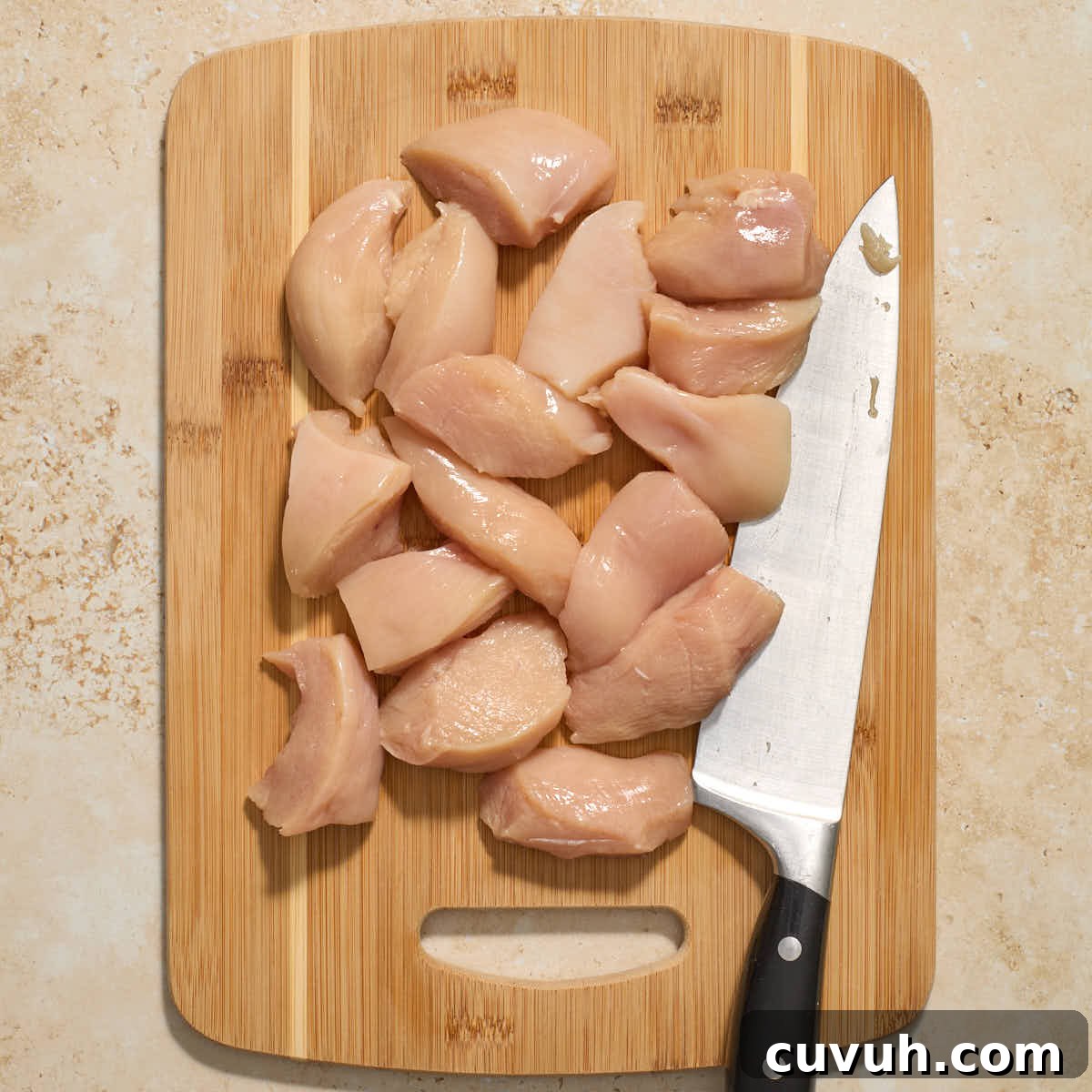 Chicken breasts sliced into pieces on a wooden cutting board.