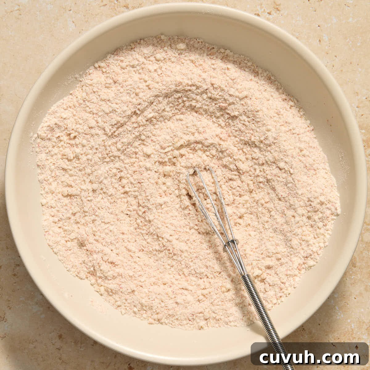 Flour and parmesan coating mixed together in bowl with a whisk.