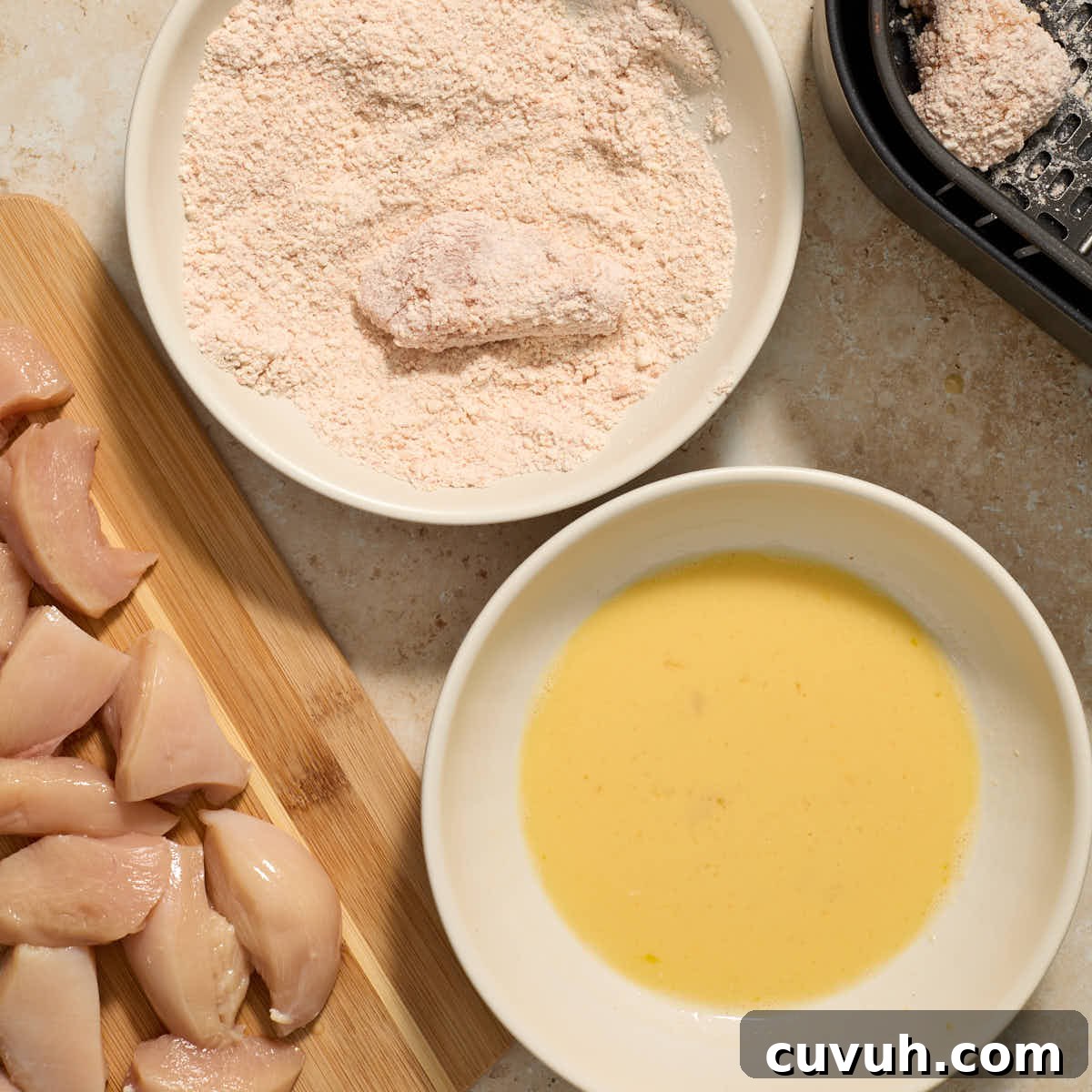 Piece of chicken being coated in the flour mixture.