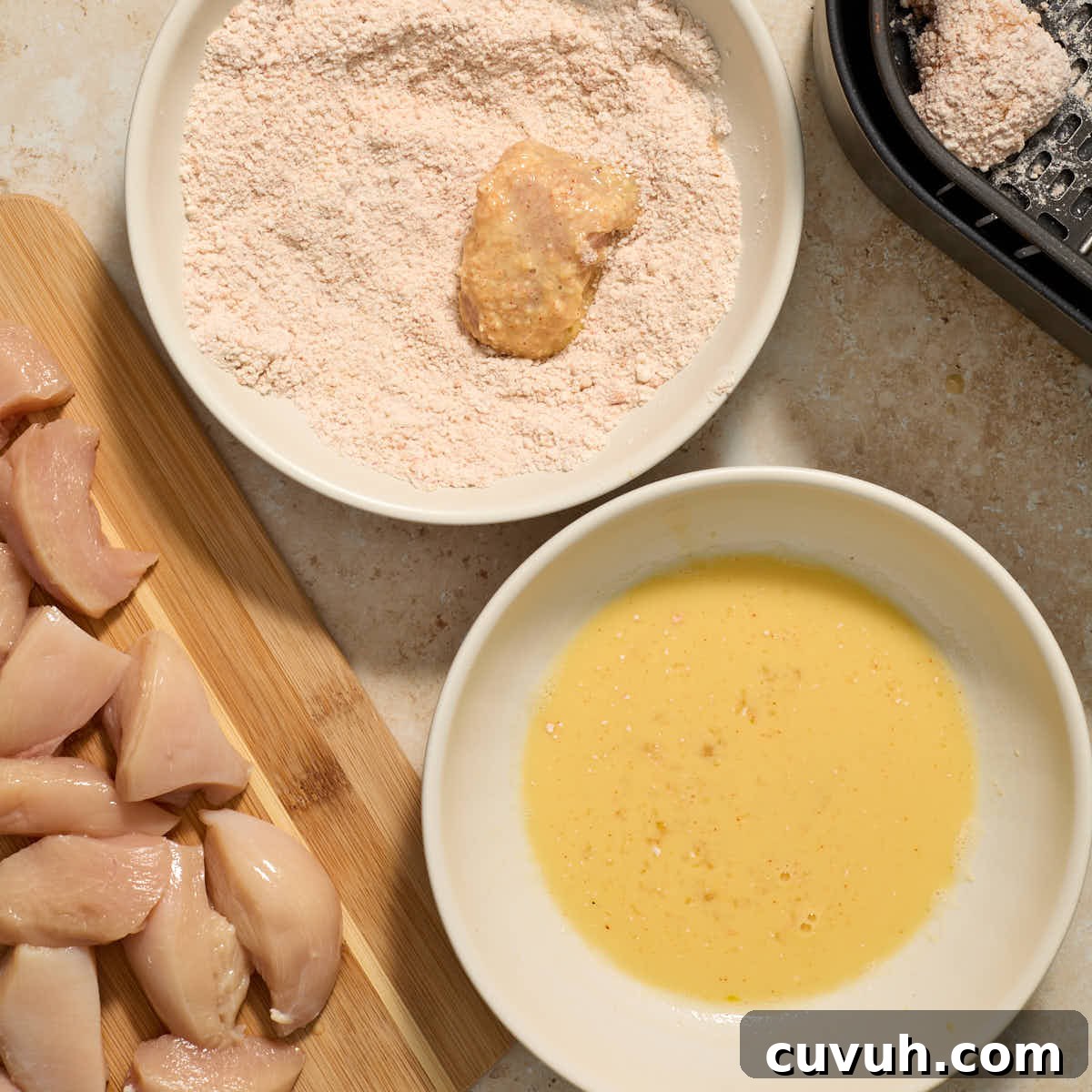 Piece of chicken being coated in a second layer of the flour mixture.