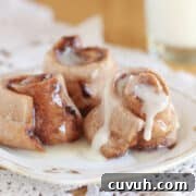 Three rolls with icing on a small white plate.