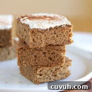 Stack of cake bars with frosting on a white plate.
