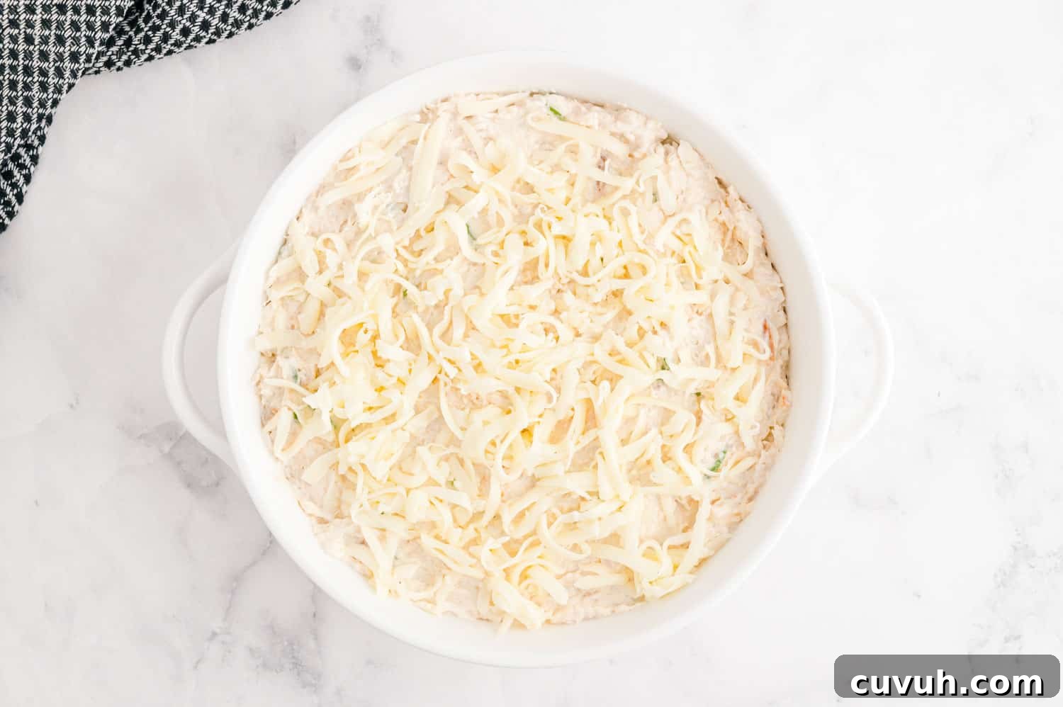 Unbaked dip in a round white baking dish.