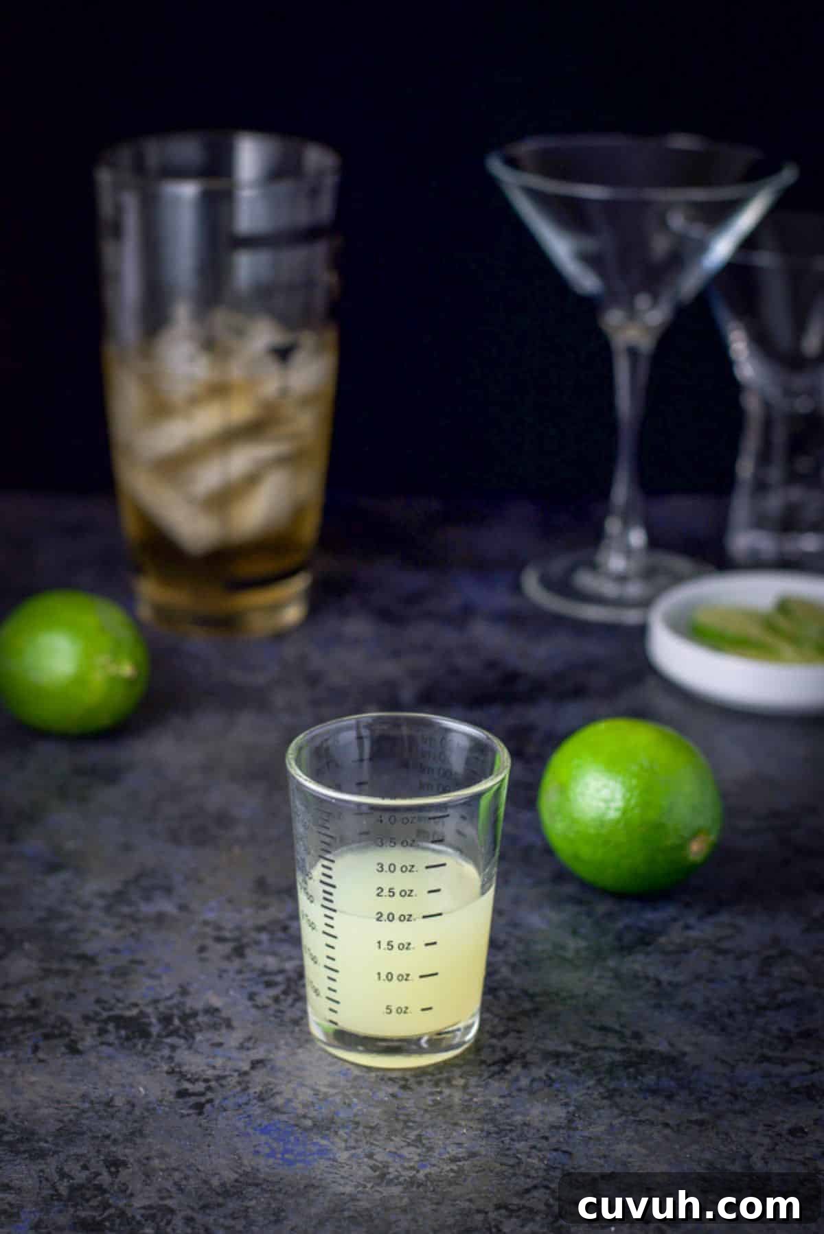 Lime measured out with other limes on the table along with the cocktail shaker in the background