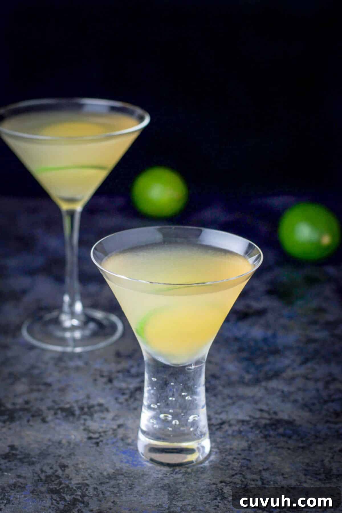 shorter bubble martini glass of the cocktail in front and the taller one behind