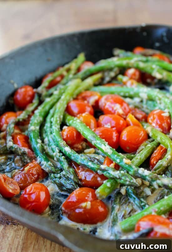 asparagus and cherry tomatoes in a cast iron pan.