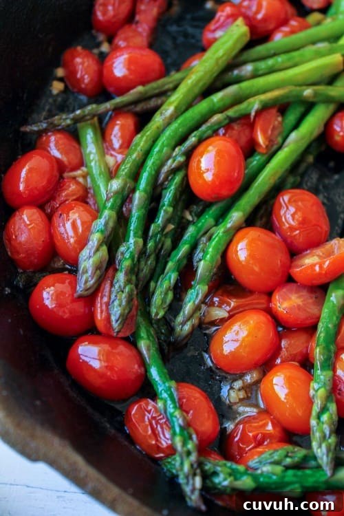asparagus and cherry tomatoes in a cast iron pan.