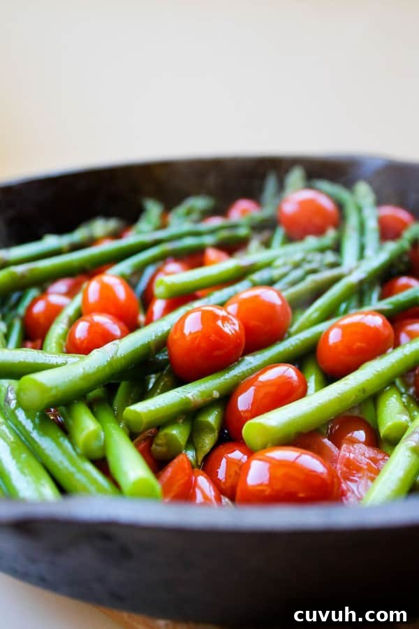asparagus and cherry tomatoes in a cast iron skillet.
