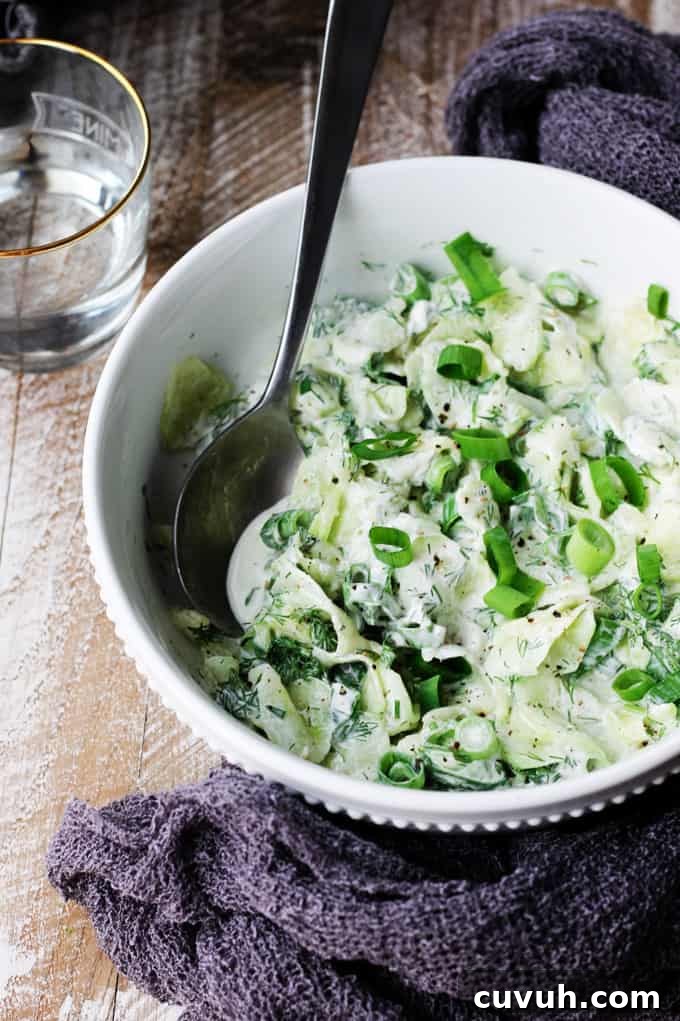 Polish cucumber salad in a white bowl with spoon in and towel around