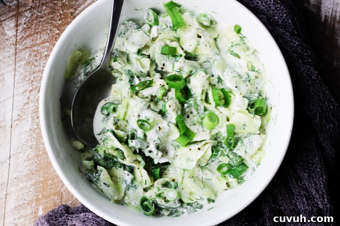 Polish cucumber salad in a white bowl with spoon; overhead shot
