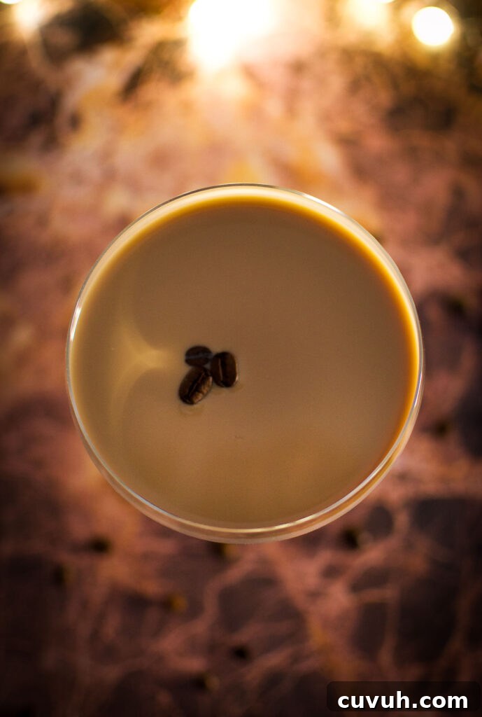 overhead image of a batida de cafe (Brazilian coffee cocktail) garnished with three espresso beans on a brown stone surface